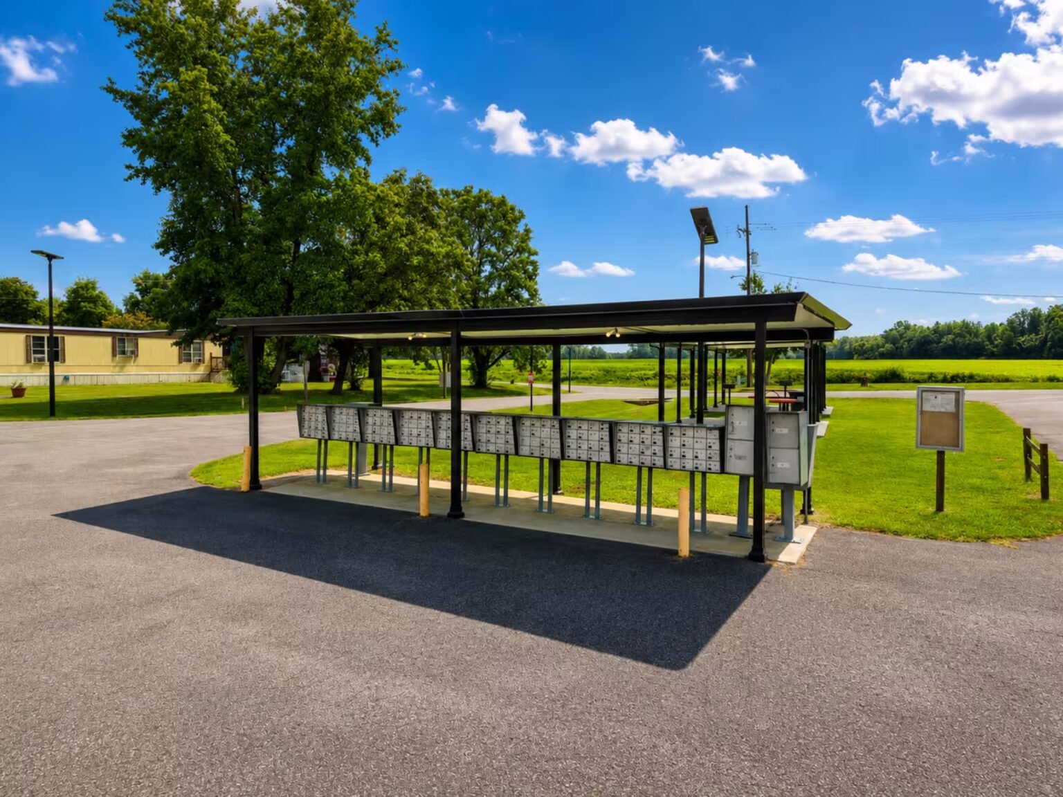 Covered picnic shelter with green roof at a park under blue sky with white clouds