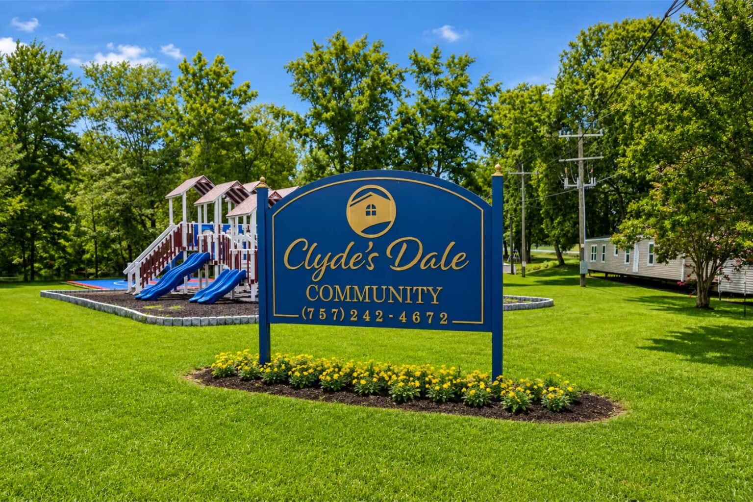 Blue Spring Circle apartments sign stands beside a colorful children's playground surrounded by green lawns and trees.