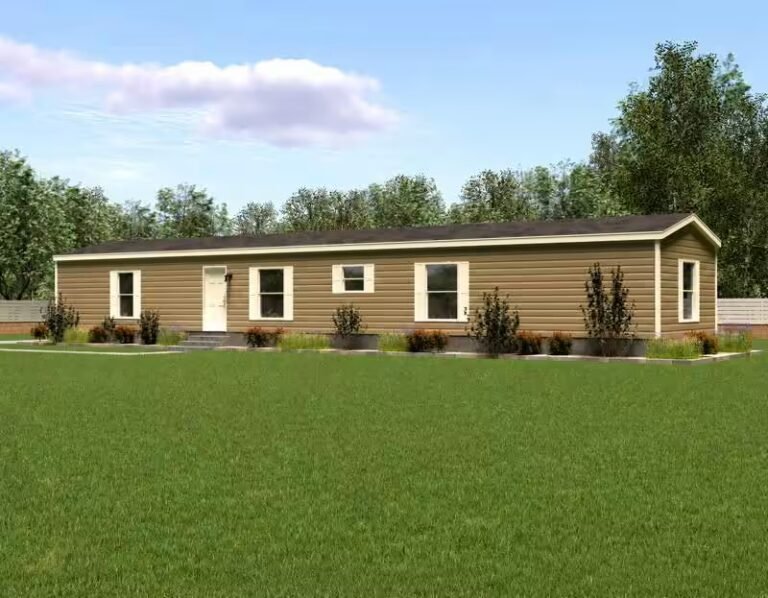 Long single-story beige manufactured home with white doors sits on green lawn under blue sky.