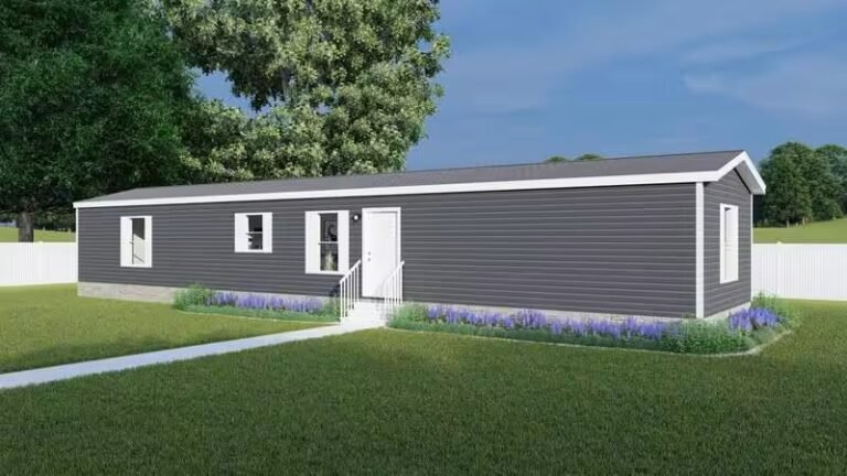 Gray single-story mobile home with white trim on a green lawn under an overcast sky.