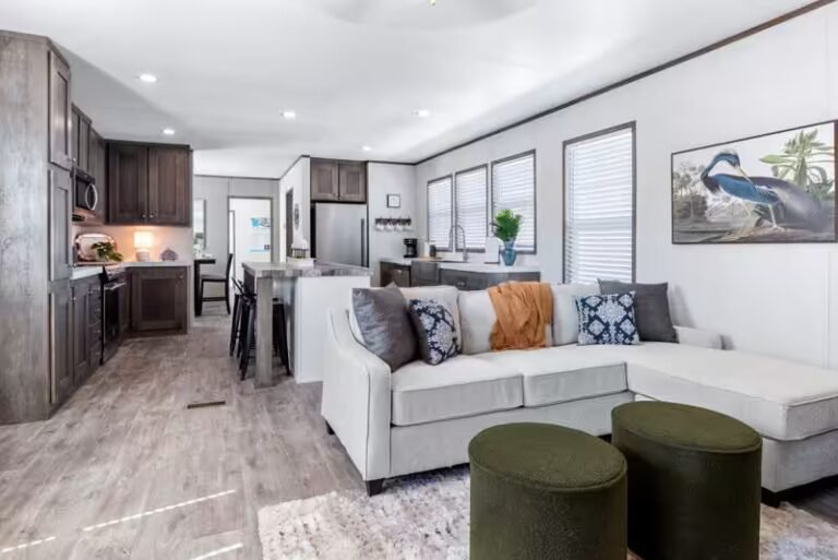 Modern living room with a large white sectional sofa, three olive-green round ottomans, and open kitchen view.