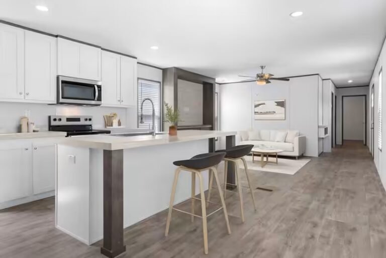 White modern kitchen with center island and black bar stools over gray wood-look flooring.