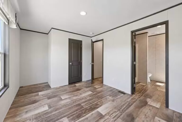 Renovated empty room with light hardwood-style flooring and white walls, open doorways leading to hall bathroom and closet